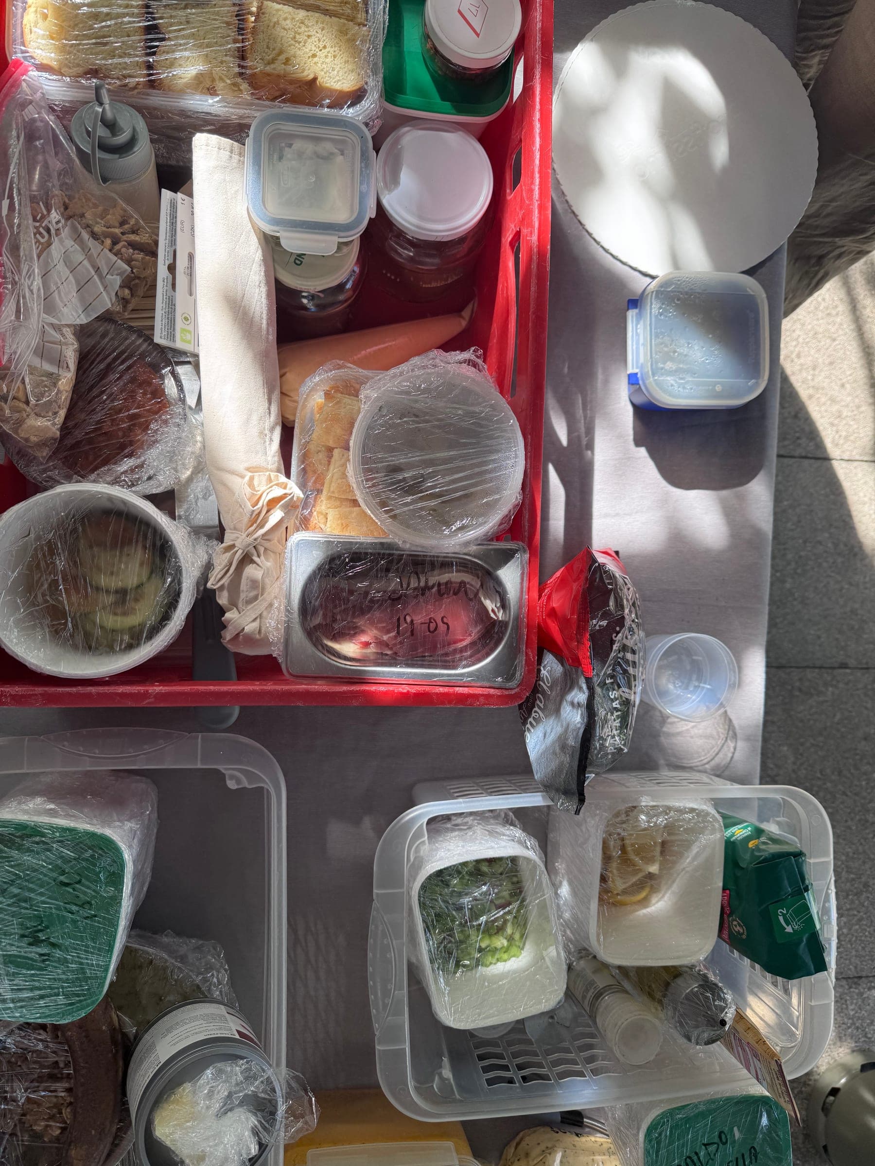 Catering-Vorbereitung: rote Kiste mit Brot, Gläsern und frischen Zutaten auf dem Tisch